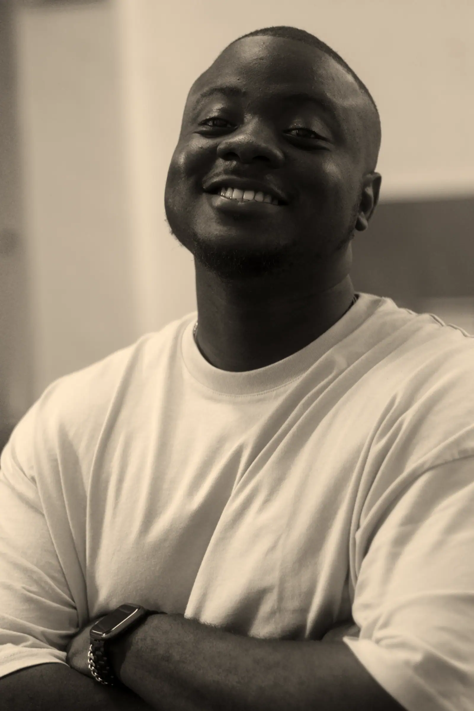 David laughing with his arms crossed, in a white T-shirt.